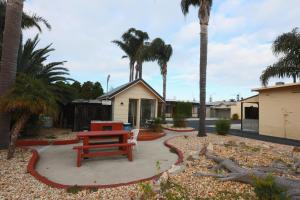 a picnic table in a yard with palm trees at The Esplanade Motel in Lakes Entrance