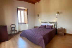 a bedroom with a bed with purple comforter and a window at Casa de Sampaio - Castelo Mendo in Castelo Mendo