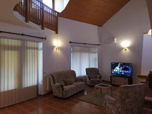 sala de estar con sillas y TV de pantalla plana en Villa Zala, en Zalakaros