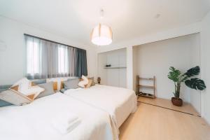 Yamada的住宿－Plage，卧室配有一张白色的大床和盆栽植物