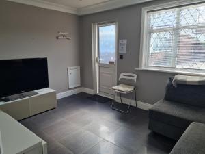 a living room with a flat screen tv and a chair at Private luxury Annex apartment with secure free parking in Chessington