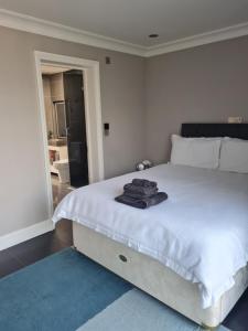 a white bed with a pile of towels on it at Private luxury Annex apartment with secure free parking in Chessington