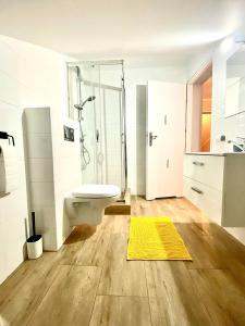a bathroom with a shower toilet and a yellow rug at Pokoje gościnne Lisa in Władysławowo