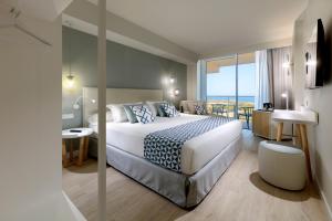 a hotel room with a bed and a view of the ocean at Palladium Hotel Menorca in Arenal d'en Castell