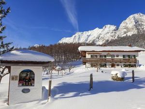 un edificio en la nieve frente a una montaña en Scheffaulehen Ferienwohnungen en Ramsau