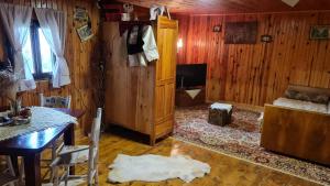 ein Wohnzimmer mit Holzvertäfelung und einem Tisch sowie ein Zimmer mit einem Bett in der Unterkunft Miliceva ruza in Zlatibor