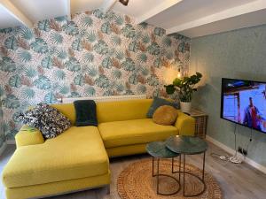 a living room with a yellow couch and a tv at Tiny House de Eikhof in Hengelo