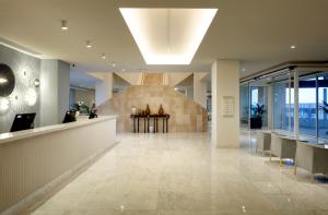a lobby of a building with a table and chairs at Palladium Hotel Menorca in Arenal d'en Castell