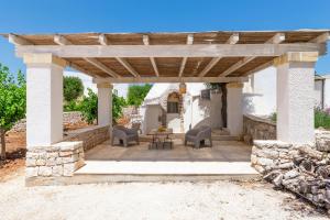 a wooden pergola with chairs and a table on a patio at Charming Villas - Villa d'Itria with trullo in Ostuni