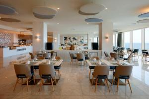 a restaurant with tables and chairs and a bar at Palladium Hotel Menorca in Arenal d'en Castell