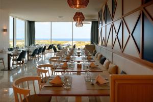 a row of tables in a restaurant with windows at Palladium Hotel Menorca in Arenal d'en Castell +37 photos