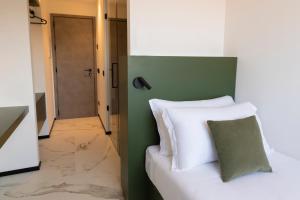 um quarto com uma cama branca e uma parede verde em The City Hotel em Ancona