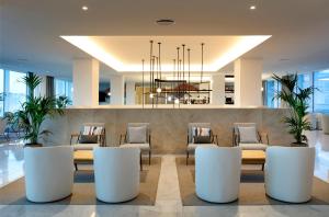 a lobby with a table and chairs and a chandelier at Palladium Hotel Menorca in Arenal d'en Castell