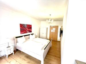 a bedroom with a white bed and wooden floors at Anker Self-Check-In Hotel in Lindau