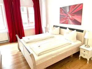 Cama en habitación con cortinas rojas en Hotel Garni Anker, en Lindau