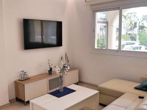 a living room with a couch and a tv on the wall at Apartamento Puerto Marina Beach in La Carihuela