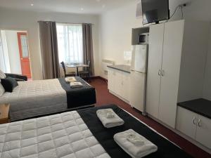 a hotel room with two beds and a kitchen at The Esplanade Motel in Lakes Entrance