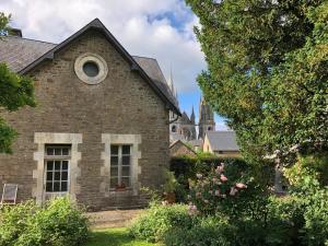 an old brick house with a church in the background at Villa des Roses in Pontmain