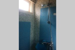 a bathroom with a blue tiled shower with a window at Beachhouse direct aan zee in IJmuiden
