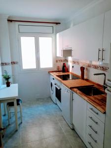 a kitchen with white cabinets and a sink and a window at Tirwal Suite Judería in Teruel