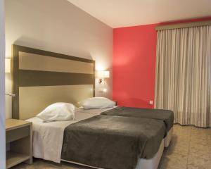 a bedroom with a bed and a red wall at Akti Dimis Hotel in Tigaki