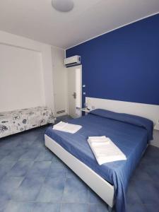 - une chambre bleue avec un lit et des serviettes dans l'établissement B&B Stella Marina, à Capo dʼOrlando