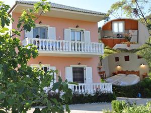 una casa rosa con un balcón blanco en Villa Vasiliki, en Vitalades