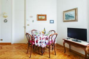 una sala da pranzo con tavolo, sedie e TV di Imperatrice apartment by Wonderful Italy a Sanremo