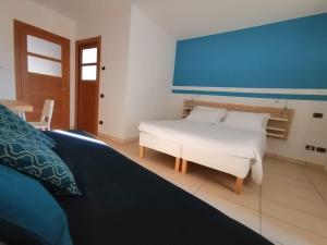 a bedroom with a white bed and a blue wall at Dimora della Posta in Mondovì