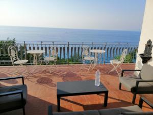 eine Terrasse mit Stühlen, Tischen und Meerblick in der Unterkunft Ellysblue in Pizzo