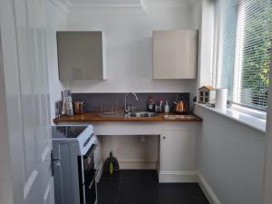 a small kitchen with a sink and a stove at Private luxury Annex apartment with secure free parking in Chessington