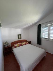 a bedroom with a white bed and a window at Lucija Apartmani in Ražanj