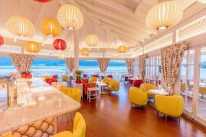 a restaurant with yellow and red chairs and tables at Hotel Schloss Seefels in P&ouml;rtschach am W&ouml;rthersee