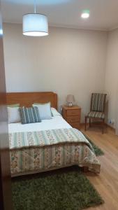 a bedroom with a bed and a chair in it at vivenda do Sobreiro AL in Serpins