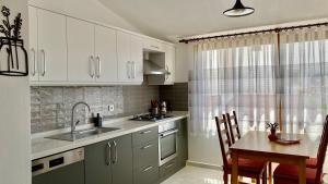 a kitchen with white cabinets and a table and a sink at Katya's home in Datca