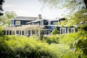 a blue house is seen through the trees at Hotel Villa Brinkly in Snekkersten