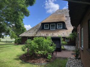 a house with a thatched roof and a yard at Haubarg alte Strandvogtei in Westerhever