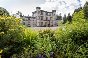 um velho castelo com um jardim em frente em Melville Castle Hotel em Edinburgo