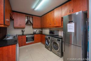una cucina con armadi in legno e frigorifero in acciaio inossidabile di Lazy Lizard 41 - with Inverter a Umdloti
