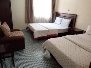 a hotel room with two beds and a chair at Lucy Guest House (B&B) in Addis Ababa
