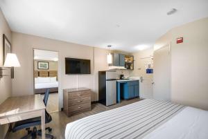 a bedroom with a bed and a desk and a kitchen at Suburban Studios Sterling - Washington Dulles in Sterling