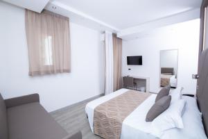 a white bedroom with a bed and a couch at Hotel Baby in Rimini