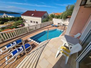 a balcony with a swimming pool and some chairs at Villa Luciana in Trogir