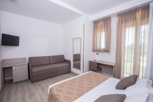 a bedroom with a bed and a couch and a mirror at Hotel Baby in Rimini