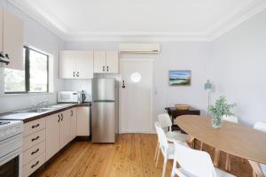 Il comprend une cuisine et une salle à manger avec une table et un réfrigérateur. dans l'établissement Beach Shack semi detached, 2 Min Walk to Beach - Wattle, à Pearl Beach