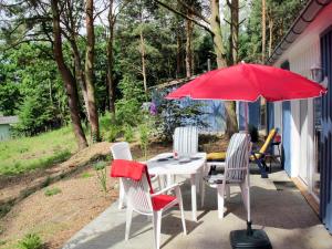 ヒンメルプフォルトにあるHoliday Home Waldhäuser-2 by Interhomeのパティオ(赤い傘付きのテーブルと椅子付)