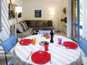 a table with red plates and a bottle of wine at Holiday Home Les maisons de la forêt by Interhome in Lacanau-Océan