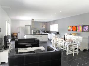 a living room with a black couch and a kitchen at Holiday Home Eugénie - GHP190 by Interhome in Grayan-et-lʼHôpital