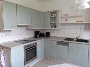 a kitchen with white cabinets and gray counter tops at Ferienwohnung Waldblick mit Balkon in Sebnitz +11 photos