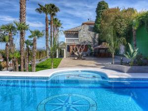 a swimming pool in front of a house with palm trees at Villa El Balcon by Interhome in Baena